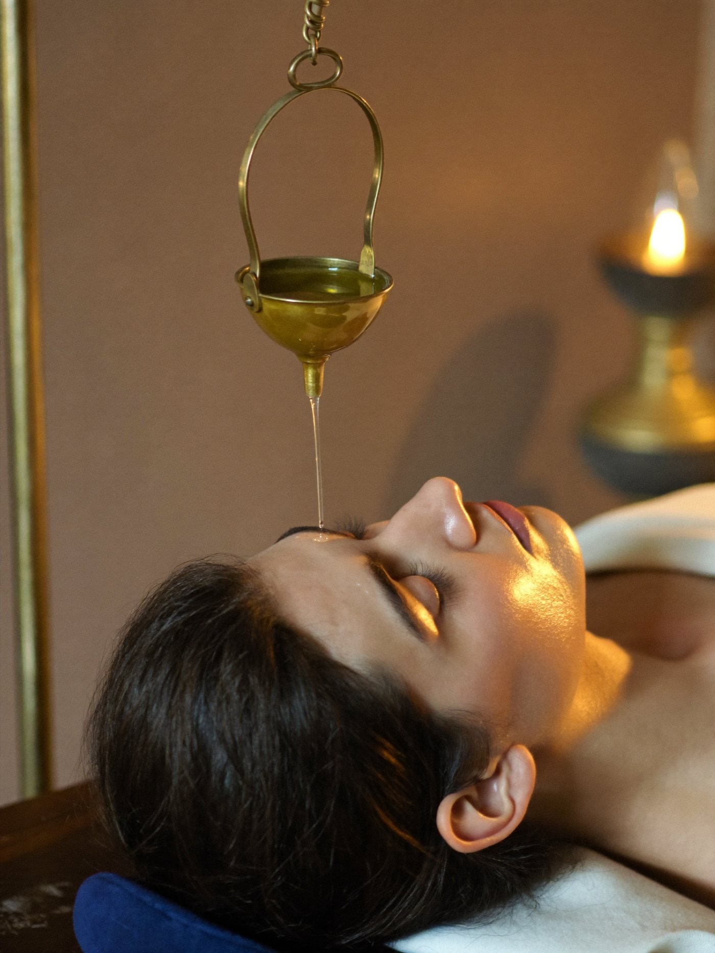 Warm medicated oil poured onto the forehead during a Shirodhara session